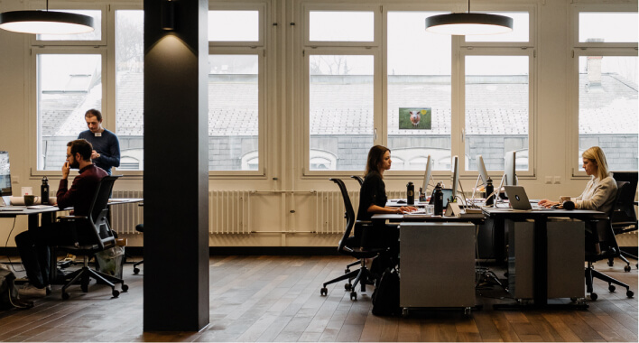 A group of people sitting around a table working on laptops.