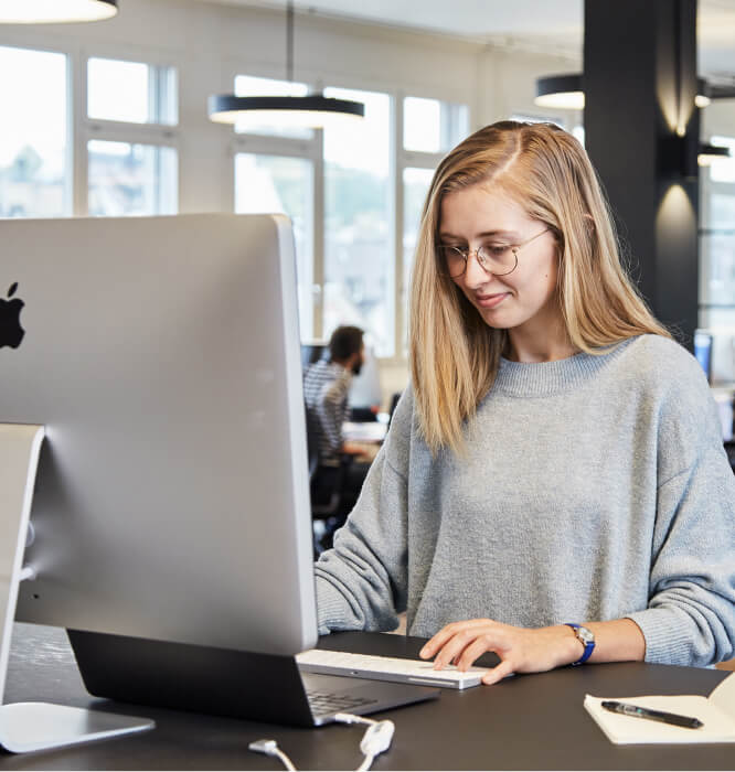 A woman sitting at a desk using a laptop computer.
